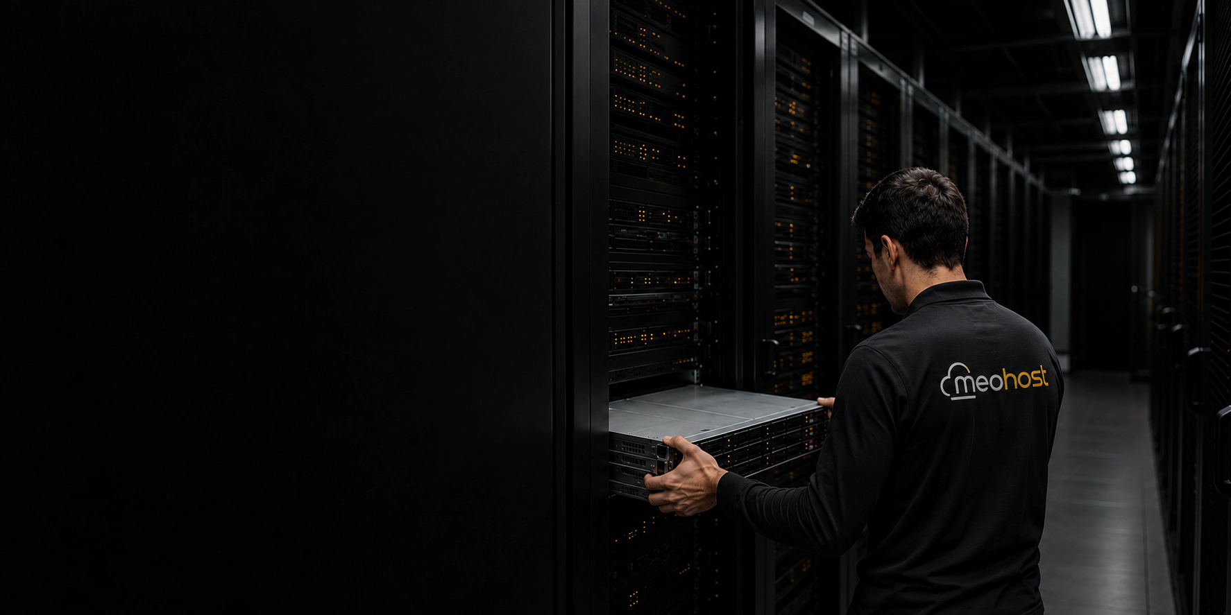 Sırtında kumaşa basılı MeoHost logosu bulunan teknik uzman, sunucuyu kabine yerleştiriyor